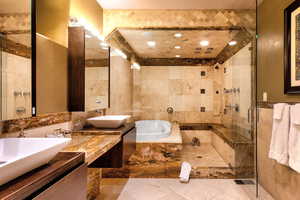 Bathroom featuring tile patterned flooring, tile walls, shower with separate bathtub, and vanity