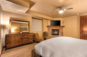 Carpeted bedroom with a fireplace, ceiling fan, and a textured ceiling