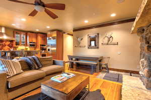 Living room with a fireplace, ceiling fan, and light wood-type flooring