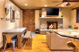 Living room featuring a fireplace, ceiling fan, and light wood-type flooring