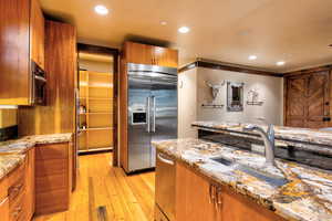 Kitchen featuring appliances with stainless steel finishes, light stone counters, light hardwood / wood-style floors, and sink