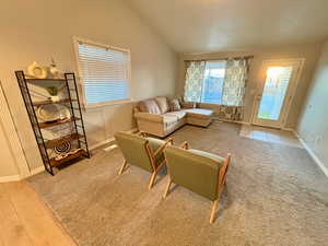 Living room with lofted ceiling and light colored carpet