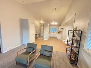 Living room featuring plenty of natural light, a notable chandelier, high vaulted ceiling, and light wood-type flooring