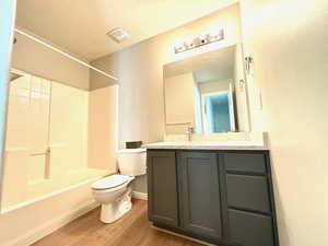 Full bathroom with hardwood / wood-style flooring, shower / bath combination, vanity, and toilet