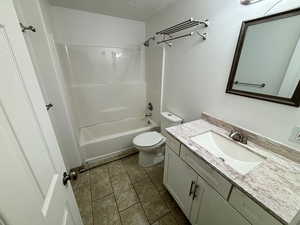 Full bathroom featuring shower / tub combination, tile patterned floors, toilet, vanity, and a textured ceiling