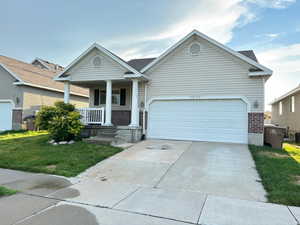 View of front of home with a garage, a porch, and a front lawn