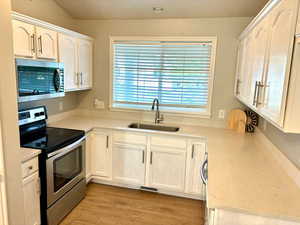 Kitchen featuring white cabinetry, sink, stainless steel appliances, and light hardwood / wood-style flooring