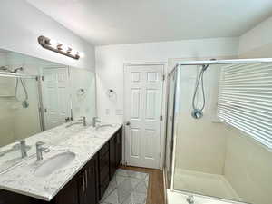 Bathroom with hardwood / wood-style flooring, a shower with door, a textured ceiling, and vanity