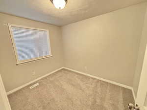 Unfurnished room featuring a textured ceiling and carpet floors