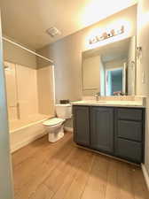 Full bathroom with shower / bath combination, hardwood / wood-style flooring, toilet, and vanity