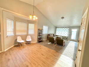 Interior space featuring light wood-type flooring, high vaulted ceiling, and an inviting chandelier