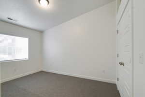 Unfurnished room with a textured ceiling and carpet floors