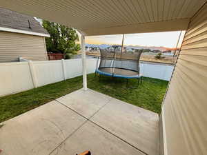 Patio terrace at dusk featuring a yard and a trampoline