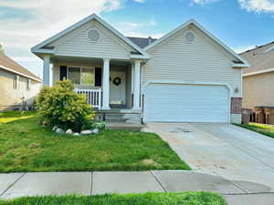 View of front of home featuring a front lawn, a porch, and a garage