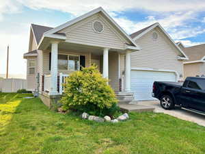 View of front of property featuring a garage, a porch, and a front yard