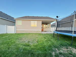 Back of property with a yard, a patio area, and a trampoline