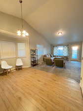 Living room with vaulted ceiling, a chandelier, and light hardwood / wood-style floors