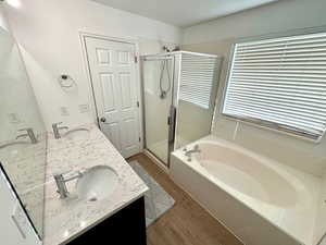 Bathroom with hardwood / wood-style flooring, shower with separate bathtub, and vanity