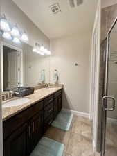 Primary bathroom with a shower with door, vanity, and tile patterned floors