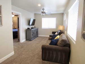 Carpeted living room featuring ceiling fan and a wealth of natural light