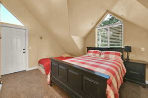 Carpeted bedroom featuring lofted ceiling