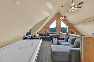 Living room featuring carpet floors, ceiling fan, and vaulted ceiling