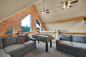 Playroom featuring ceiling fan, brick wall, vaulted ceiling, rustic walls, and carpet floors