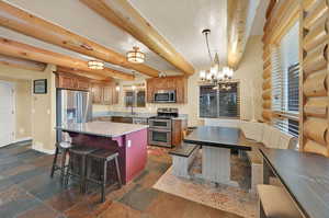 Kitchen with pendant lighting, beam ceiling, sink, a center island, and stainless steel appliances