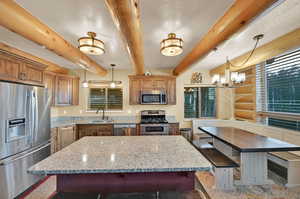 Kitchen featuring a center island, beam ceiling, hanging light fixtures, and appliances with stainless steel finishes