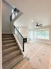 Staircase with a glass covered fireplace, recessed lighting, and ceiling fan