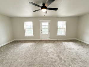 Unfurnished room featuring light carpet, a textured ceiling, and ceiling fan
