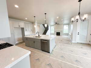 Kitchen featuring a fireplace, tasteful backsplash, decorative light fixtures, a kitchen island with sink, and recessed lighting