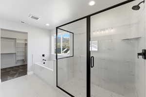 Full bathroom featuring a marble finish shower, a spacious closet, a bath, and recessed lighting