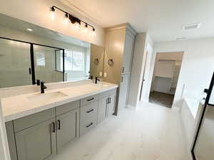 Bathroom featuring a walk in closet, double vanity, a shower stall, a bath, and light marble finish floors