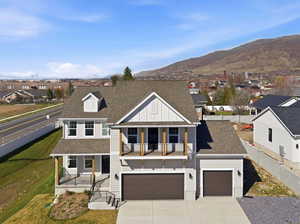View of front of house with a shingled roof, covered porch, driveway, a residential view, and an attached garage