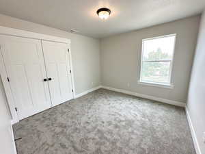 Unfurnished bedroom with carpet flooring, a closet, and a textured ceiling