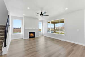 Unfurnished living room with a glass covered fireplace, a ceiling fan, recessed lighting, and light wood-type flooring