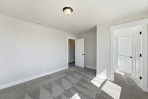 Unfurnished bedroom with dark carpet and ensuite bath