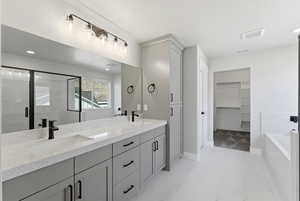 Full bath with double vanity, a spacious closet, a garden tub, recessed lighting, and a marble finish shower