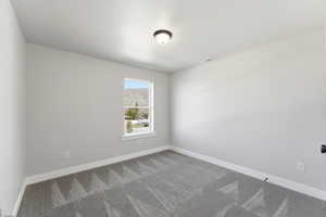 Spare room featuring baseboards and dark colored carpet