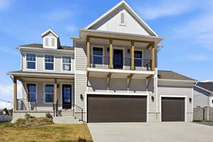 View of front of house with covered porch, board and batten siding, concrete driveway, and a front lawn