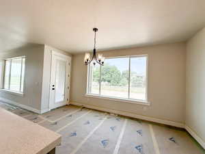 Unfurnished dining area featuring a chandelier and a textured ceiling