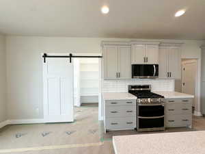Kitchen featuring stainless steel appliances, a barn door, gray cabinets, decorative backsplash, and recessed lighting