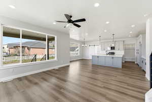 Unfurnished living room featuring a chandelier, a ceiling fan, and light wood-style floors