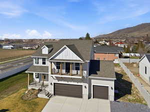 View of front of home with roof with shingles, a porch, concrete driveway, board and batten siding, and a residential view