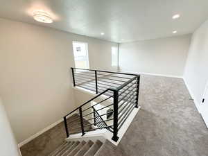 Stairs with carpet flooring, recessed lighting, and a textured ceiling
