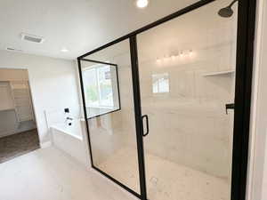 Bathroom featuring a garden tub, a stall shower, a walk in closet, and recessed lighting