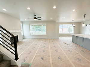 Unfurnished living room featuring stairs, a fireplace, recessed lighting, a chandelier, and a ceiling fan
