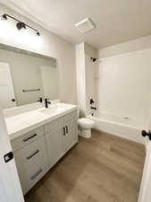 Full bath featuring tub / shower combination, dark wood-type flooring, vanity, and a textured ceiling