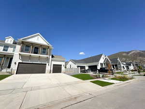View of front of home featuring concrete driveway, board and batten siding, an attached garage, a residential view, and stone siding